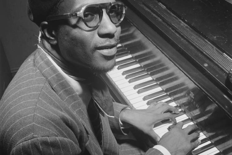 A jazz piano player looks at the camera while playing a piano.