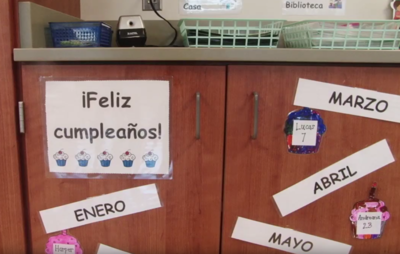 Vocabulary signs in Spanish are taped to the classroom's cabinets.