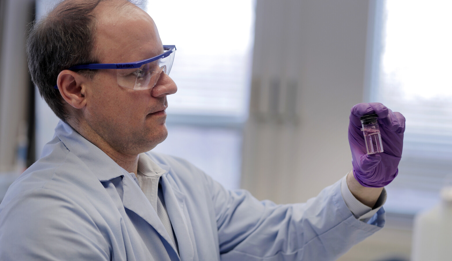 Purdue University professor Andrew Whelton looks at water sample from a faucet. The pink color shows that the sample may contain chlorine — a disinfectant used by utilities to kill bacteria. (Courtesy of Purdue University)