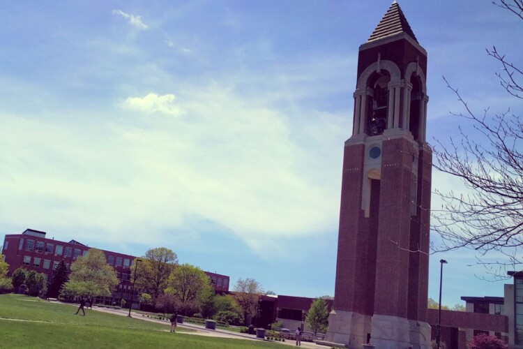 Ball State's Shafer Tower is a large brick obelisk that stands on the right of the photo, amid sunny, blue skies.