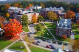 A bird's eye view of a college campus focuses on the green and sidewalks that connect the buildings together.