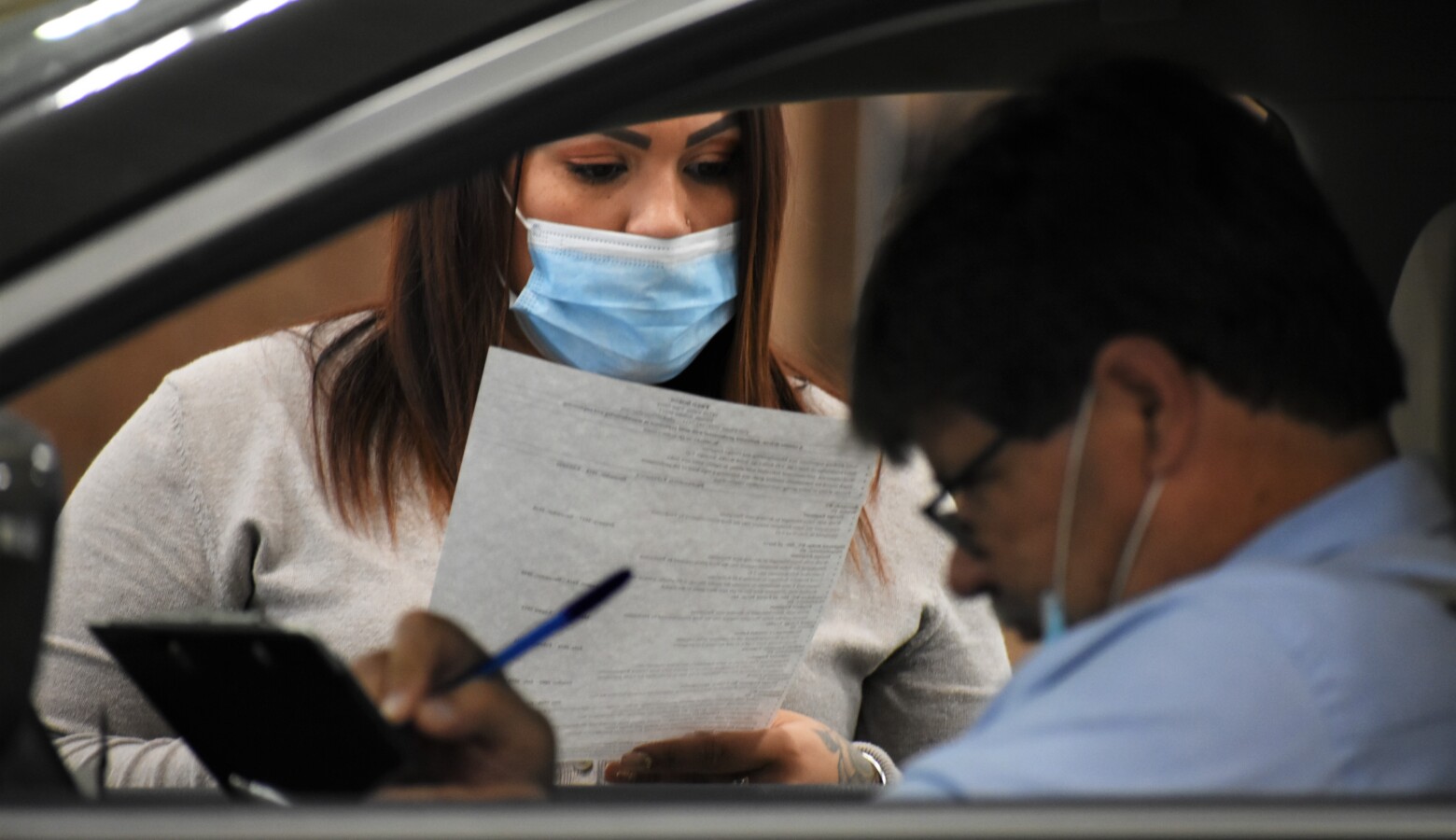 A human resources representative reads a resume at a drive-thru job fair in Elkhart. (Justin Hicks / IPB News)