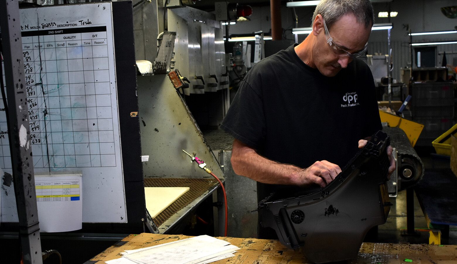 A worker at Decatur Plastic Products performs a final inspection on a piece that has just come off the assembly line. DPP specializes in molded plastic parts that are used in car dashboards and consoles. (Justin Hicks/IPB News)