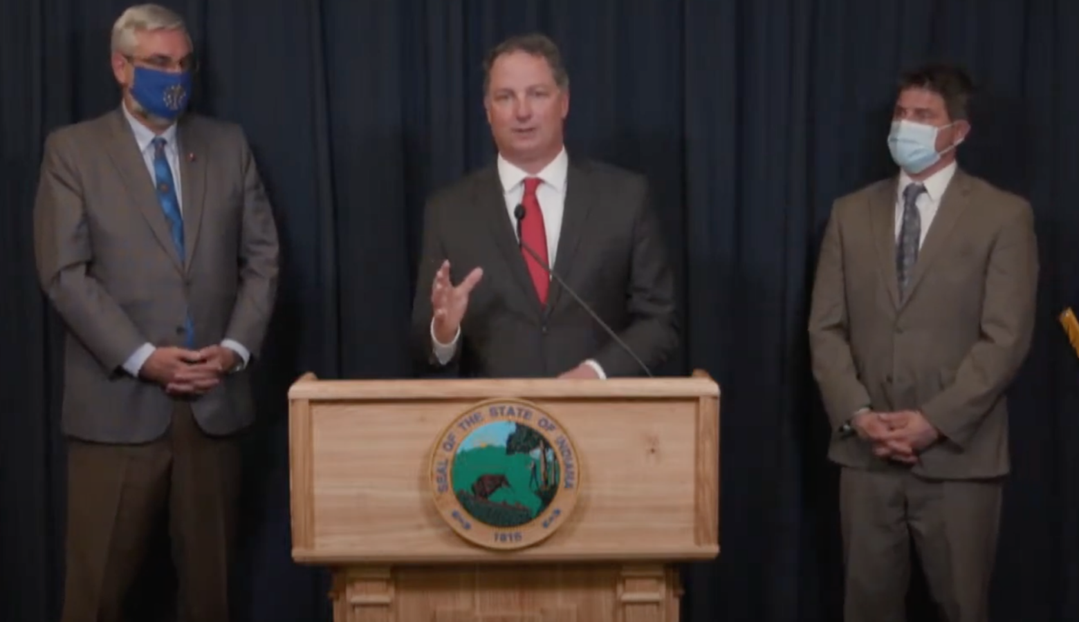 Speaker Todd Huston (R-Fishers) discusses education funding in the new state budget, flanked by Gov. Eric Holcomb, left, and Senate President Pro Tem Rodric Bray (R-Martinsville), right. (Screenshot from YouTube)