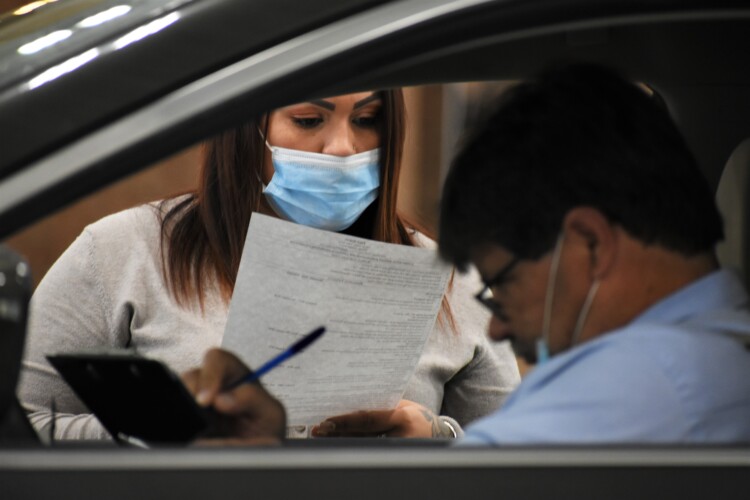A human resources representative reads a resume at a drive-thru job fair in Elkhart. (Justin Hicks / IPB News)
