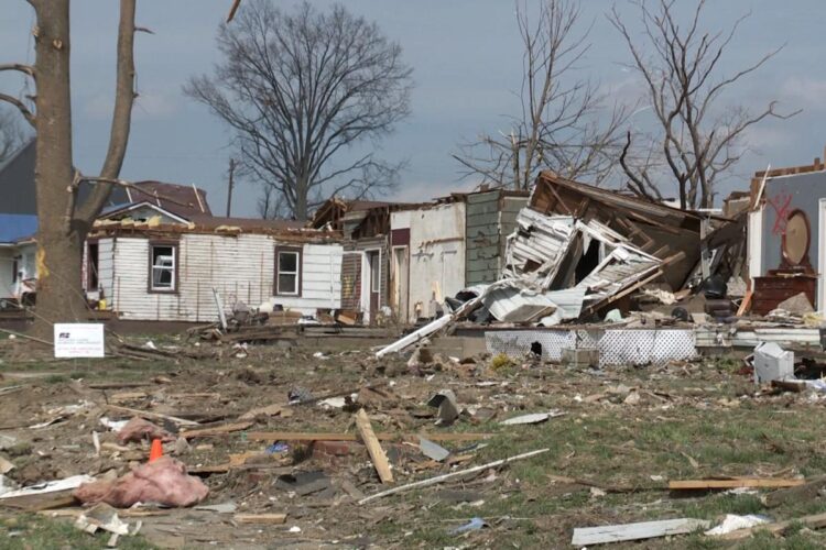 Homes destroyed by a tornado sit in a row, with yards full of debris.