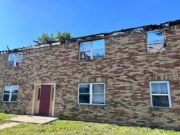 A two story brick building with no roof. Burn marks can be seen lining the top of it.