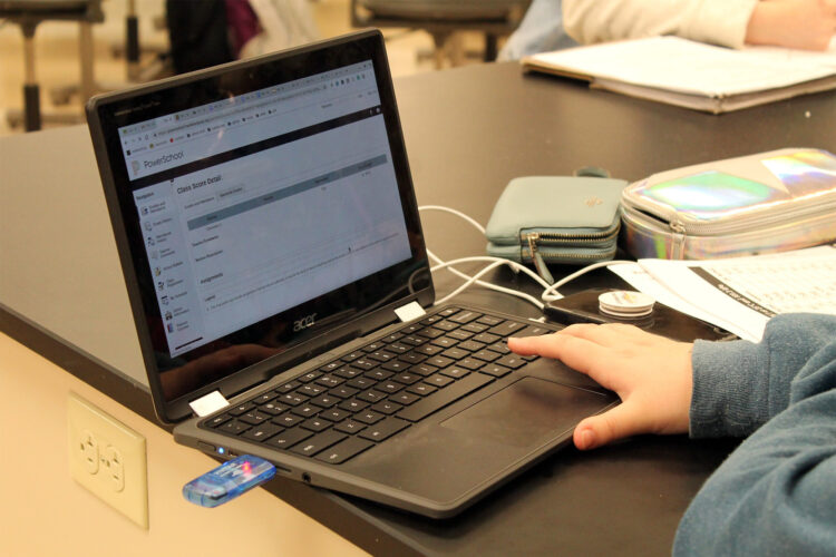 A student sits at a table while working on a computer.