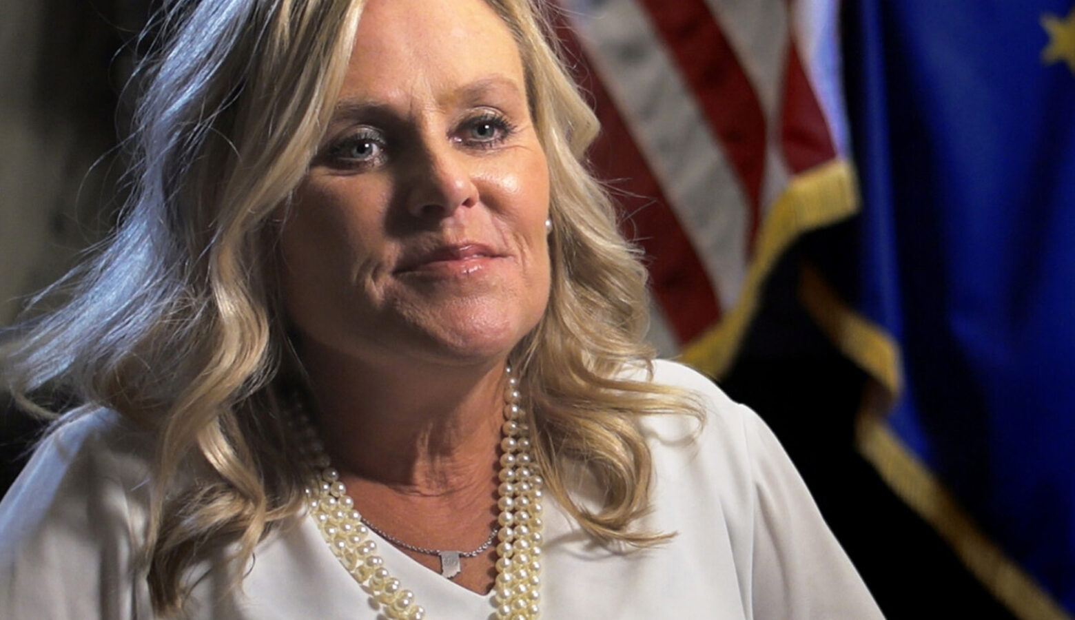 Jennifer McCormick sits for an interview with an American flag and Indiana flag in the background.