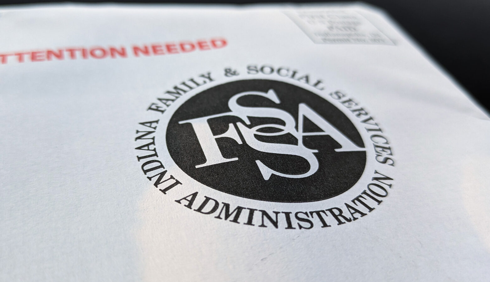 A white envelope with a black Indiana Family and Social Services Administration logo printed on it with the words "Attention needed" printed in bright red.