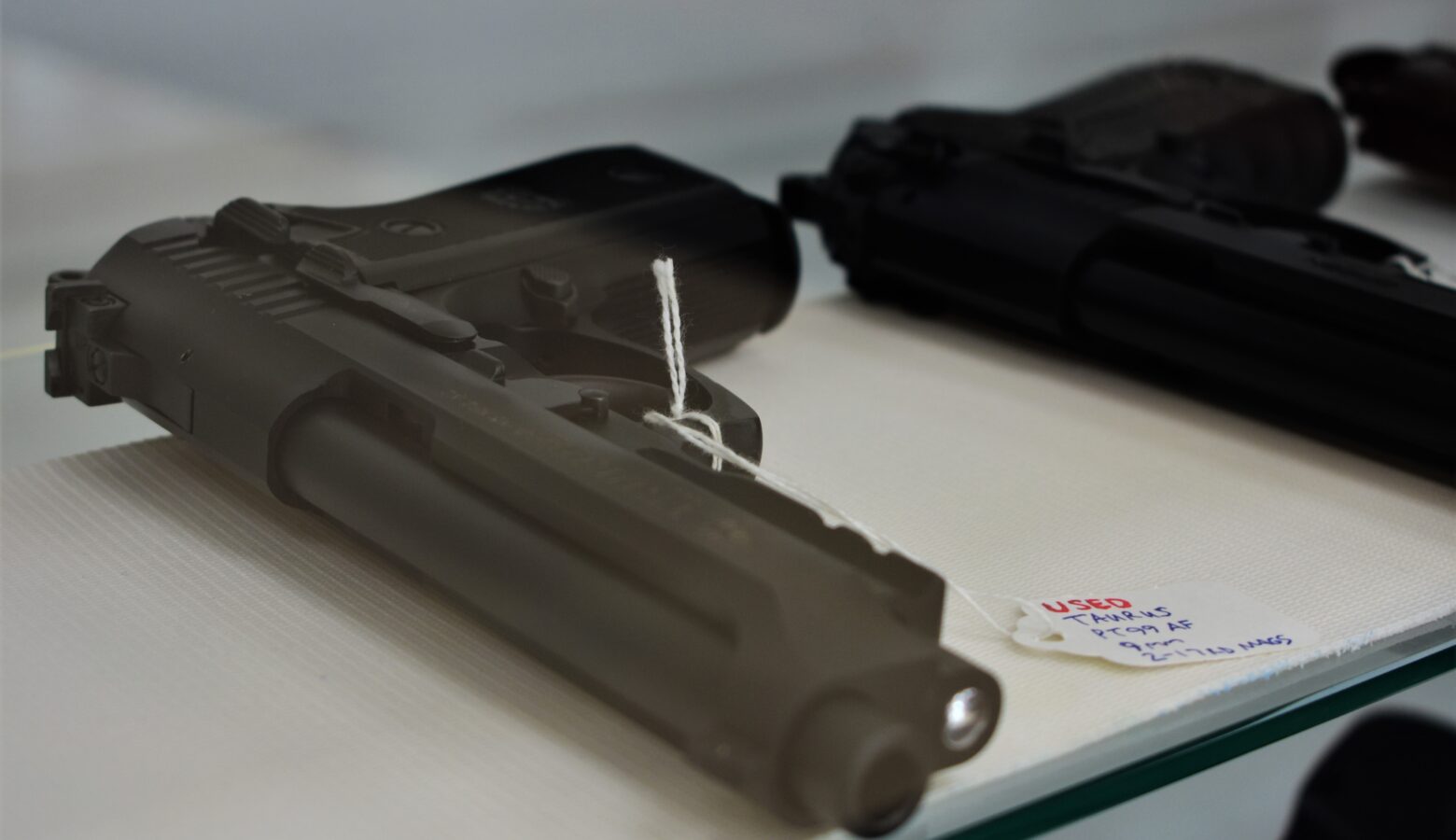 A pair of handguns on a table at a gun show. There are tags attached to the guns.