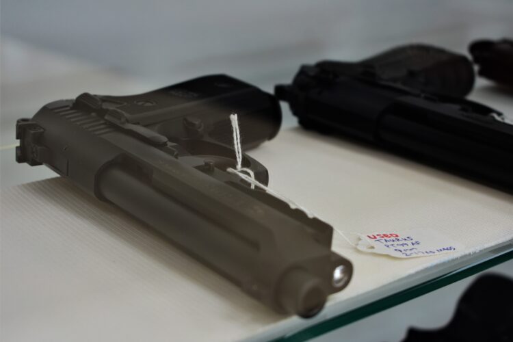 A pair of handguns on a table at a gun show. There are tags attached to the guns.