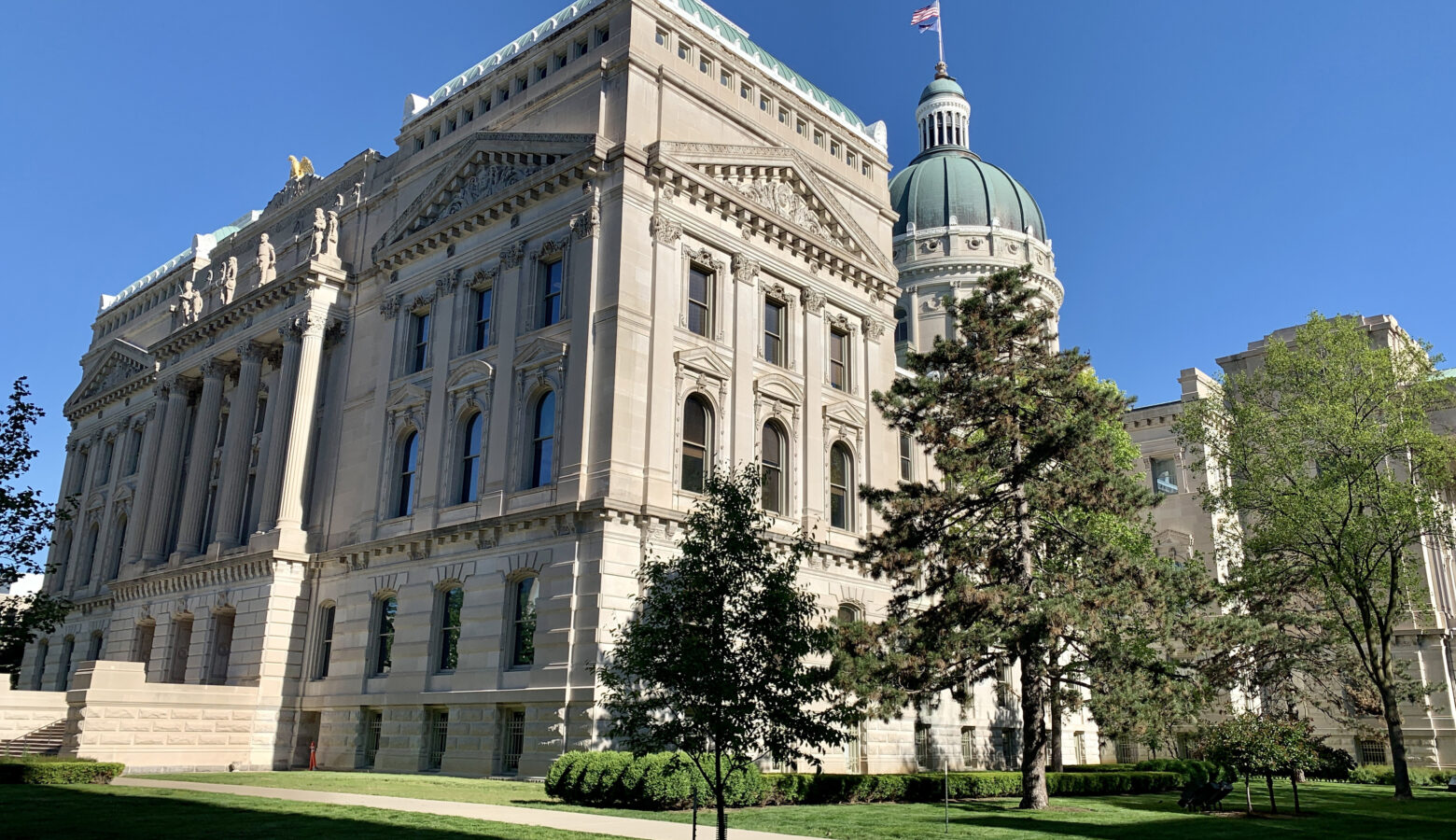 The Indiana Statehouse with trees standing in front of it.