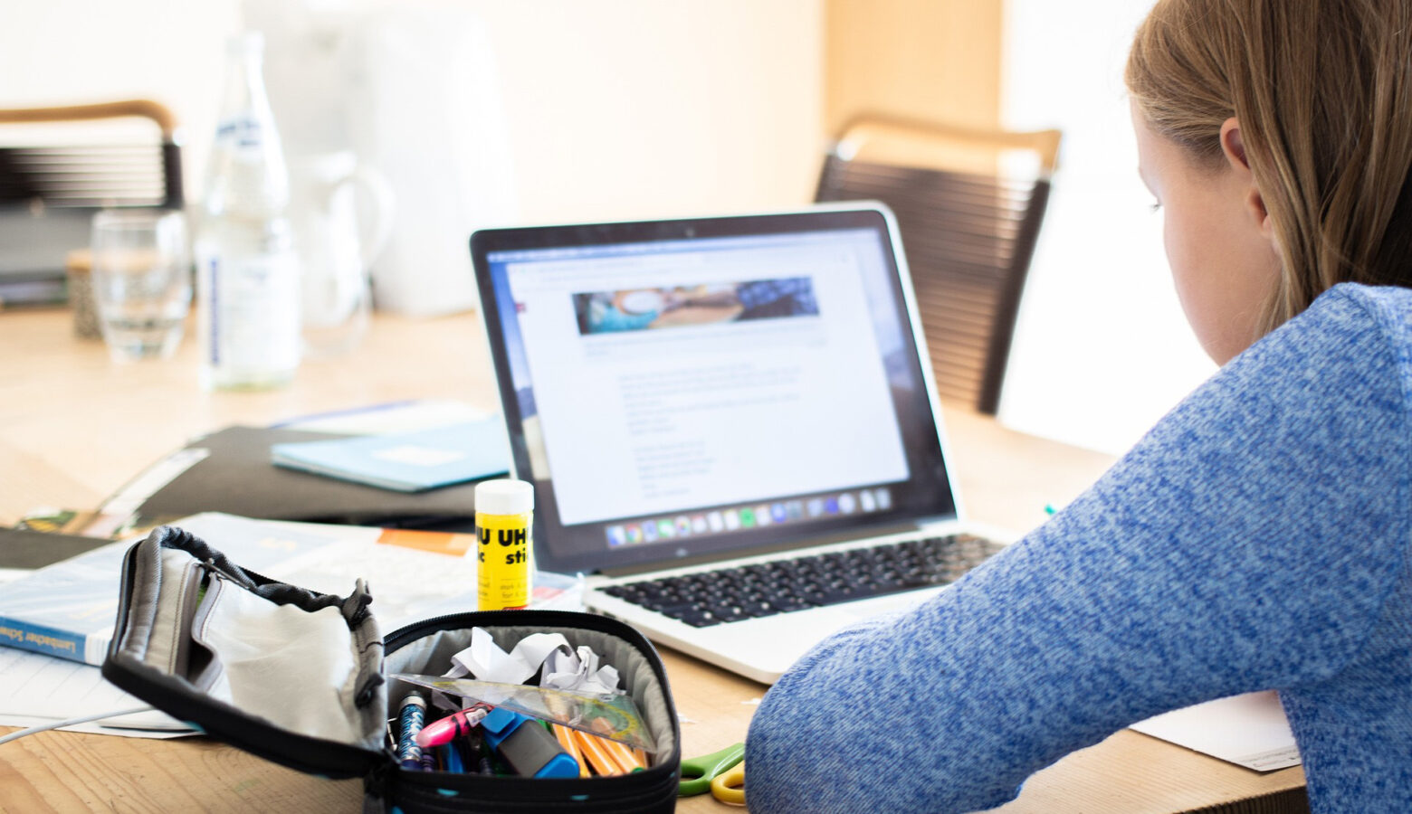 A student sits in front of a laptop at their home.