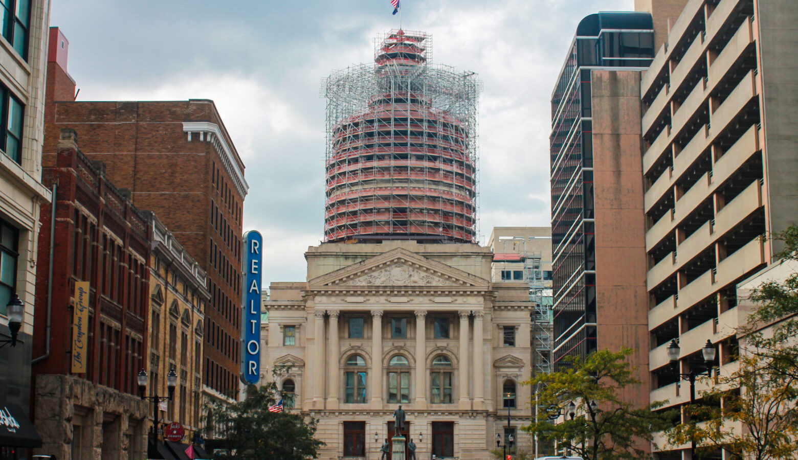 The eastern exterior of the Indiana Statehouse, framed between other buildings.