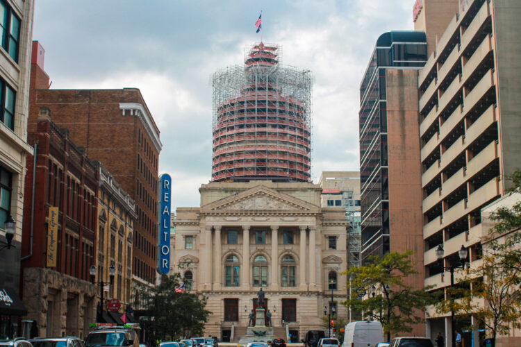 The eastern exterior of the Indiana Statehouse, framed between other buildings.