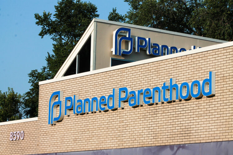 The exterior of a Planned Parenthood clinic. It is a tan brick building with the organization's logo on the outside.