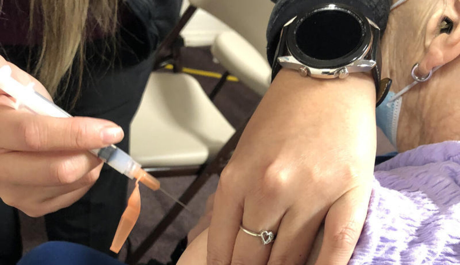 A health care provider delivering a vaccine via syringe into someone's arm.