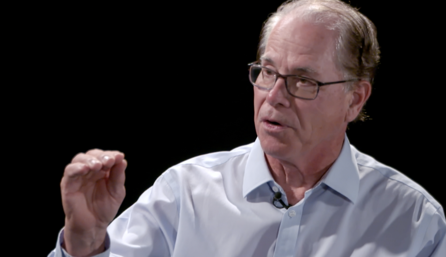 A screenshot from a video interview with Mike Braun. Braun is a White man, balding with dark, graying hair. He is wearing glasses and a light blue shirt.