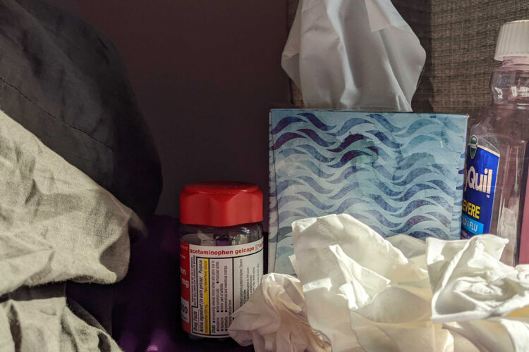 A pile of tissues sits next to a tissue box with cold medicines surrounding it.