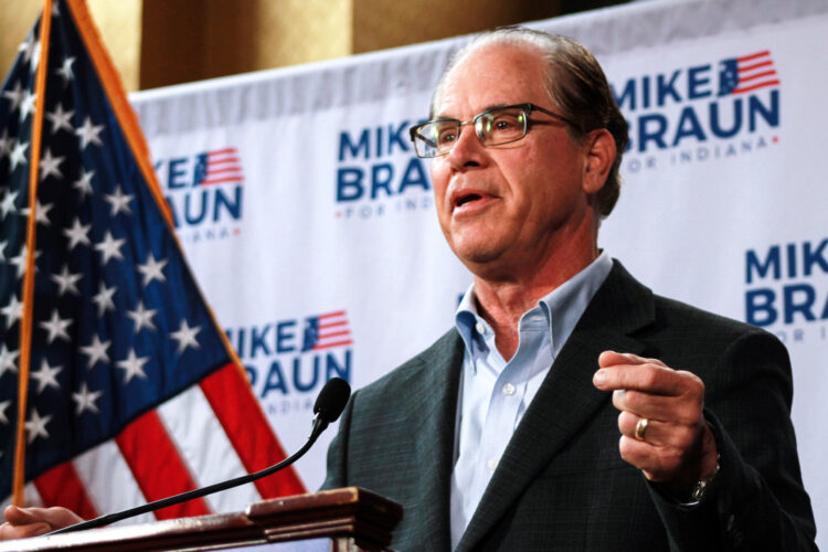 Mike Braun stands at a podium with his campaign logo on a screen behind him.