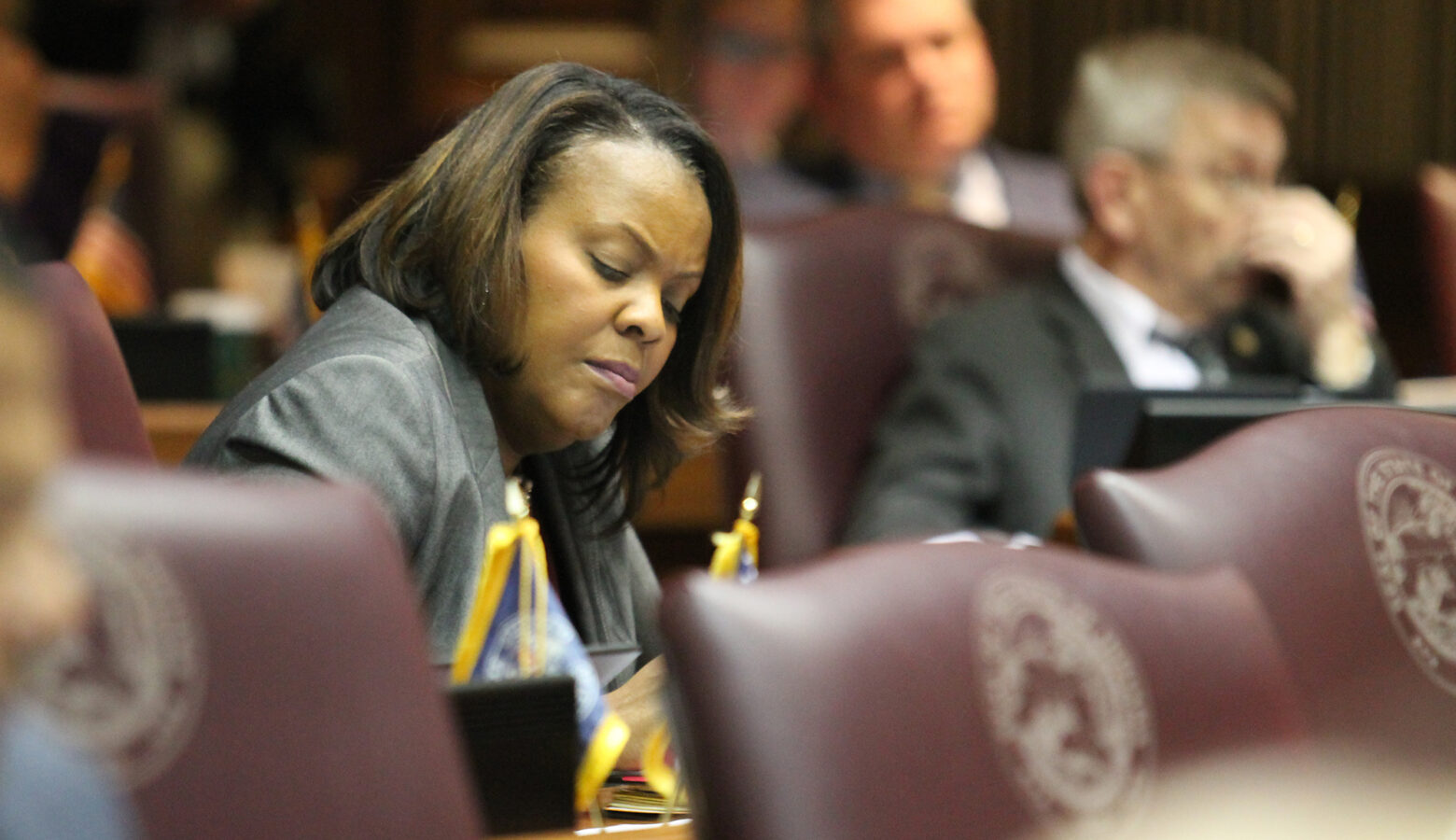 Representative Robin Shackleford sitting at her desk on the house floor. Shackleford is a Black woman, with shoulder-length dark brown hair.