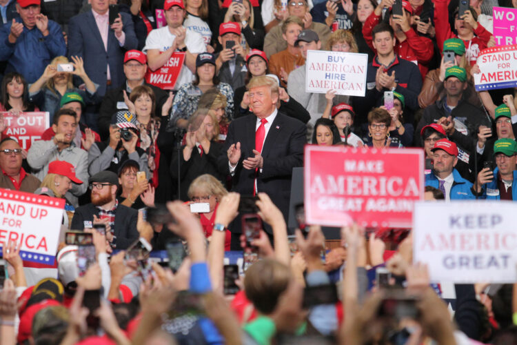 Donald Trump speaks at a rally in Indianapolis. He is surrounded by a crowd holding 'Make America Great Again' signs and cheering for him.