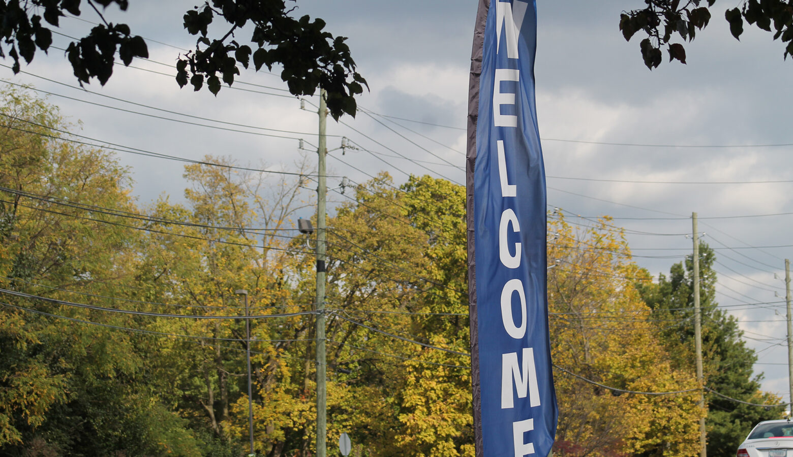 A banner with Welcome written down its length flaps in the wind in the fall.