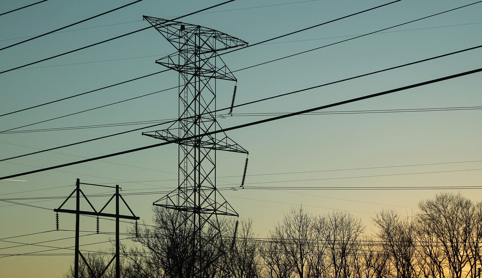 A photo of power lines near an airport at dusk.