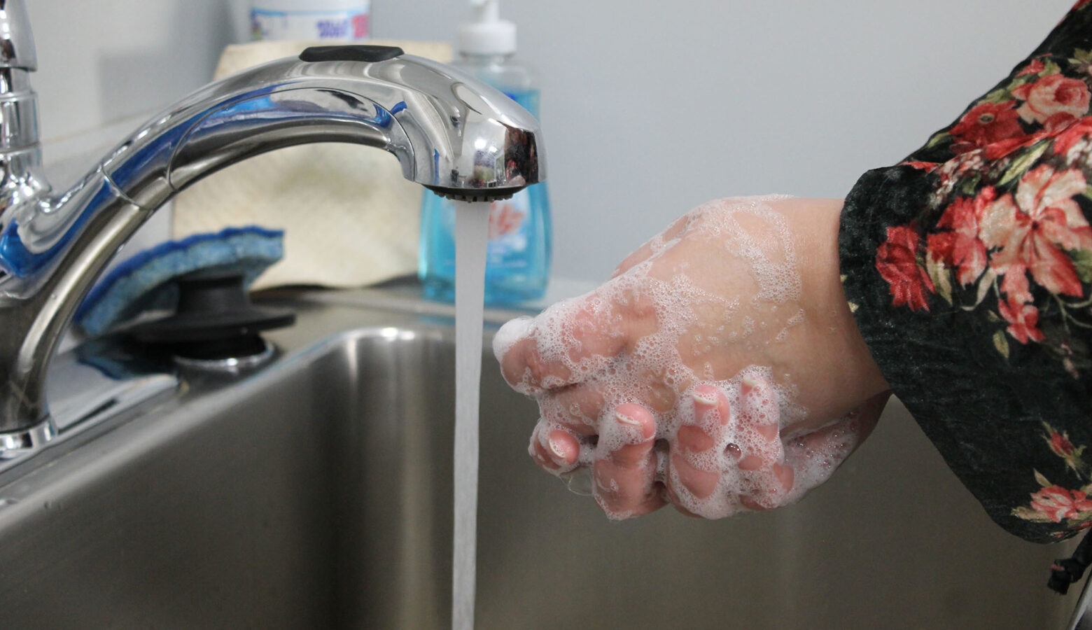 A person washes their hands with soap and water at a sink.