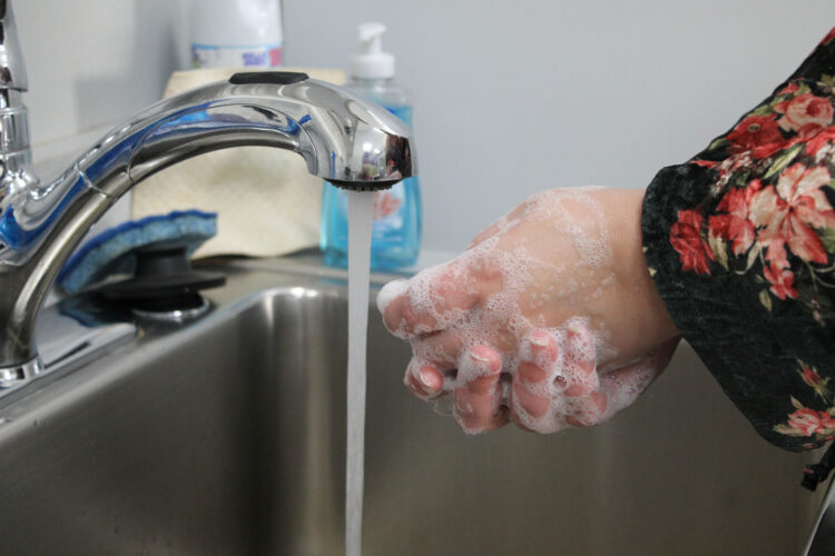 A person washes their hands with soap and water at a sink.