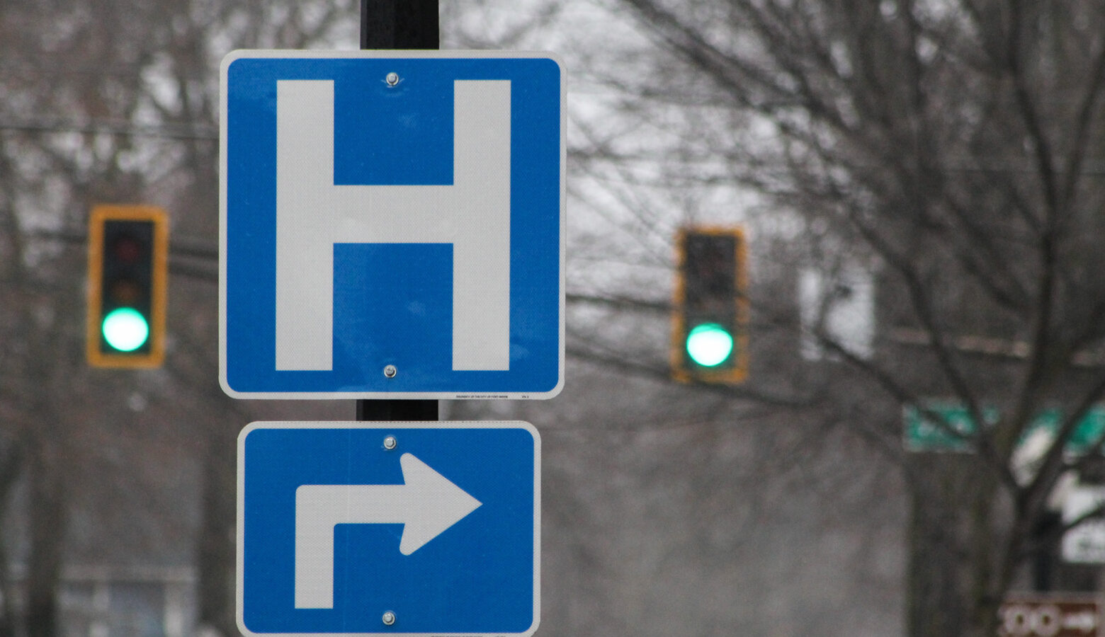 A blue sign with a white "H" indicating there is a hospital on the next turn.