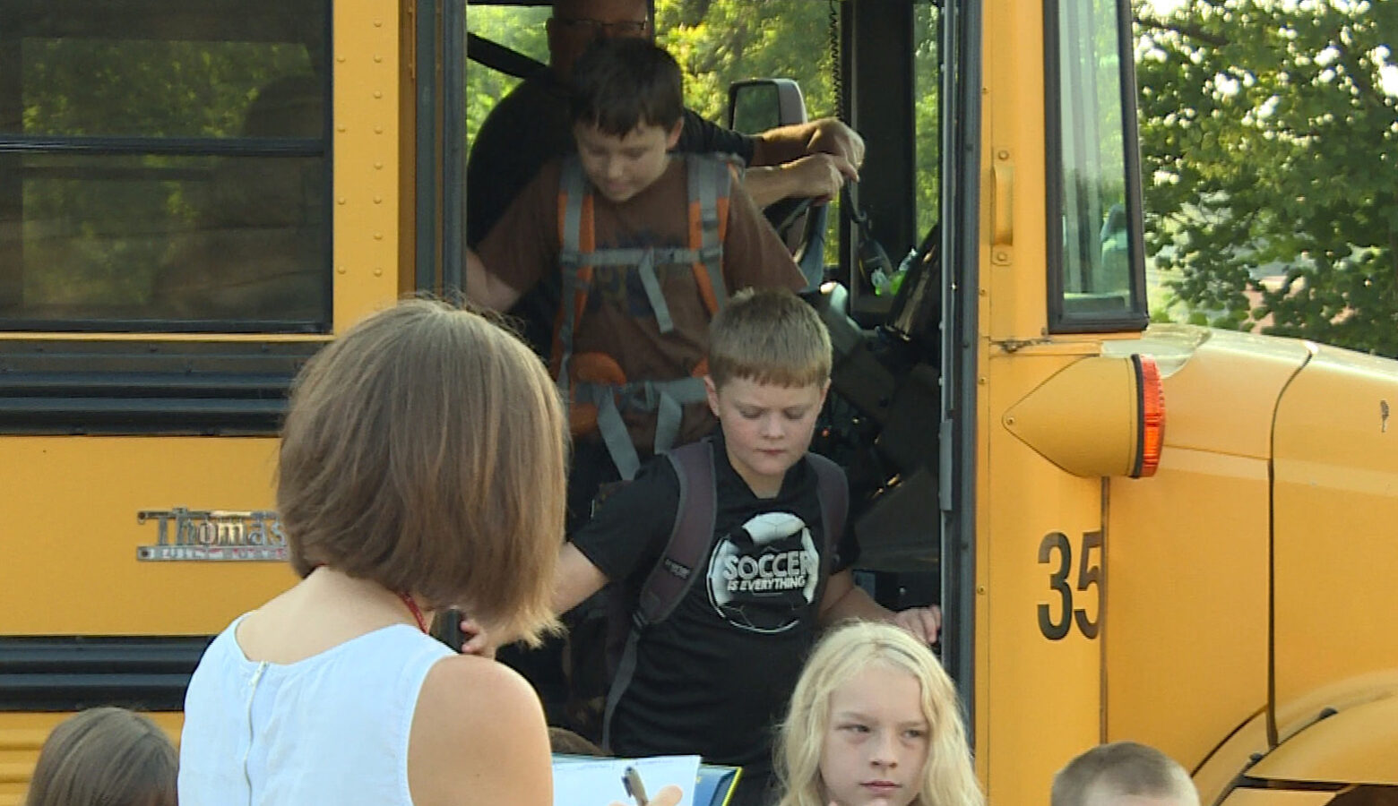 Children get off of a yellow school bus.