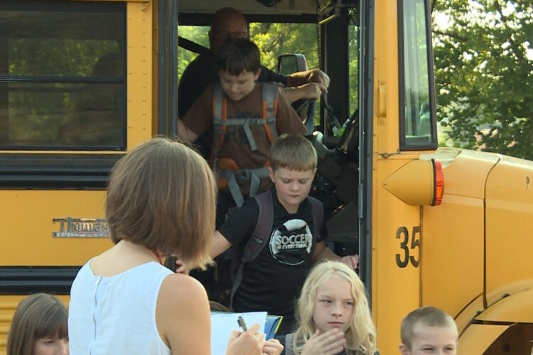 Children get off of a yellow school bus.