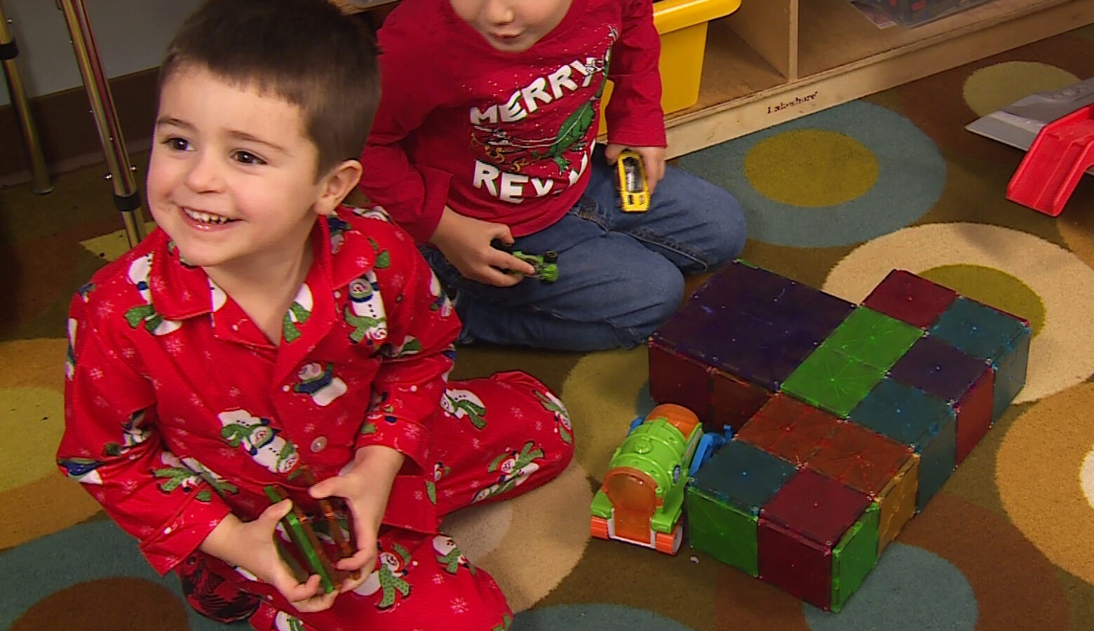 A child sits in pajamas on the floor of a preschool (it was PJs Day).