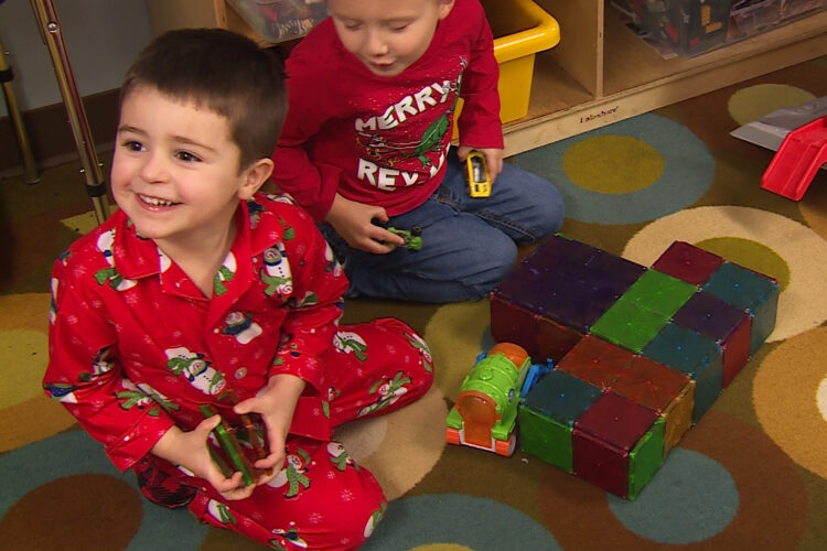 A child sits in pajamas on the floor of a preschool (it was PJs Day).