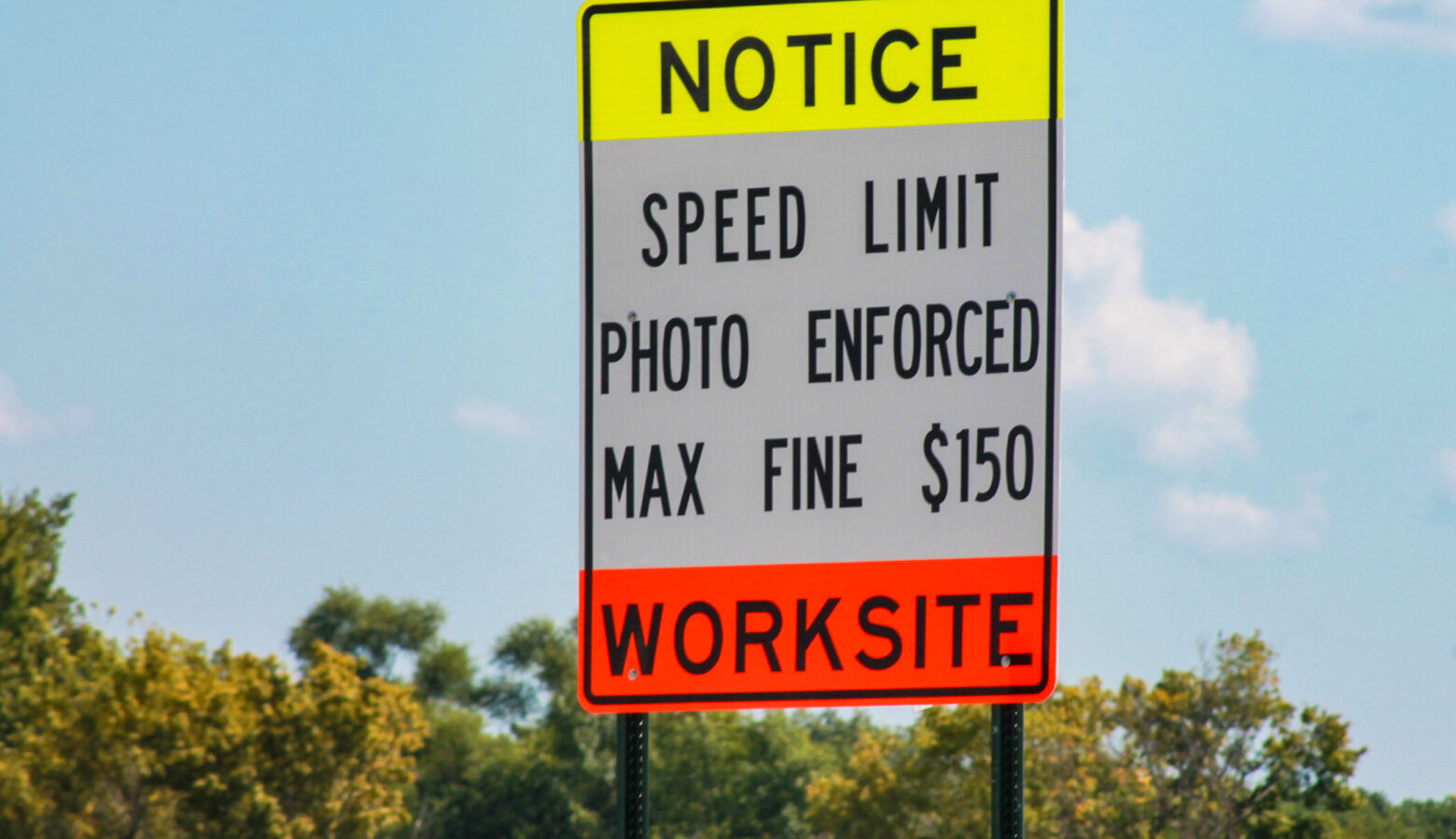 A road sign that reads "Notice Speed Limit Photo Enforced Max Fine $150 Worksite"