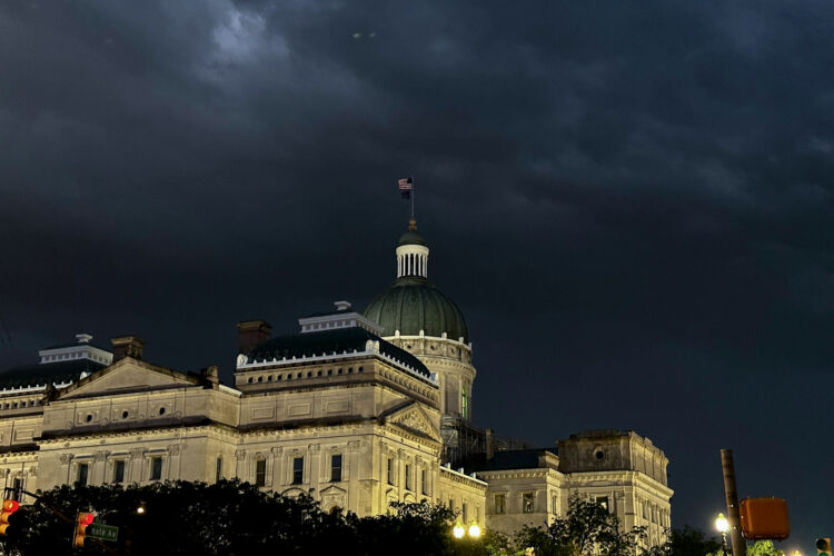 The Indiana Statehouse at night. A bit of moonlight peaks out from nighttime clouds.