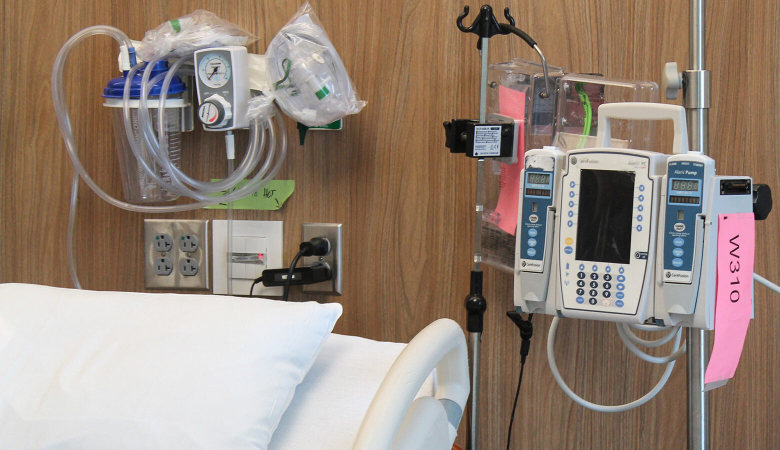 Medical equipment and machines sit next to a hospital bed in a hospital room.