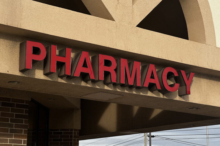 A sign on the entrance to a building reads "Pharmacy" in red, block letters.