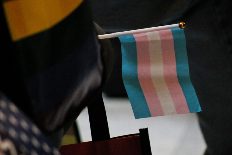 A small, desktop-sized transgender pride flag is wedged into a chair during a protest at the Statehouse.