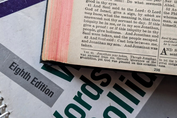 A Bible sits on top of a grammar textbook.