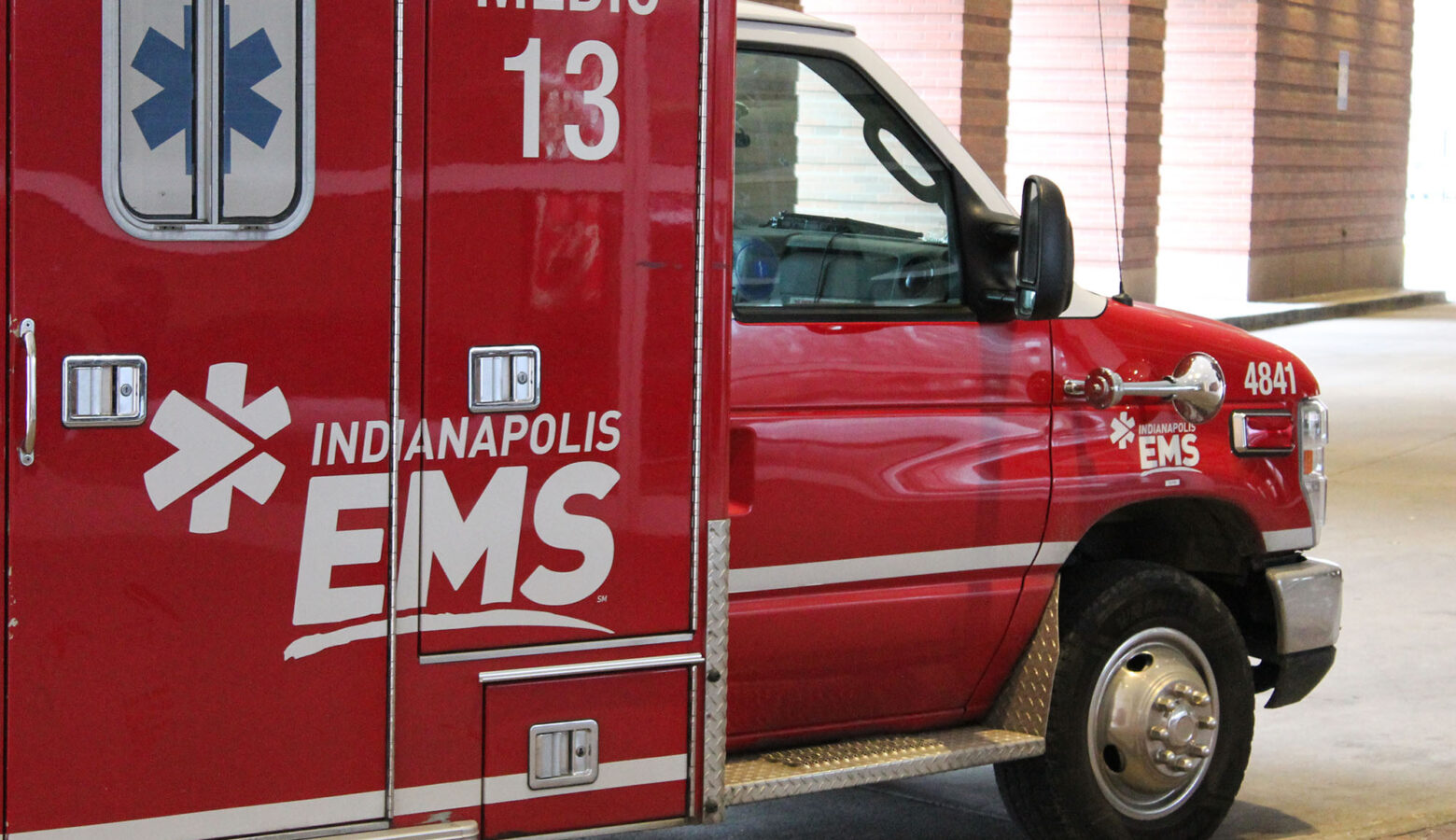 A red Indianapolis EMS unit with a white logo and a blue medic decal is parked outside.