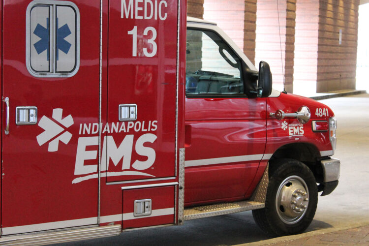 A red Indianapolis EMS unit with a white logo and a blue medic decal is parked outside.