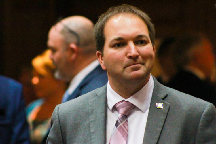 J.D. Prescott is a White man with brown hair. He is wearing a suit and tie.