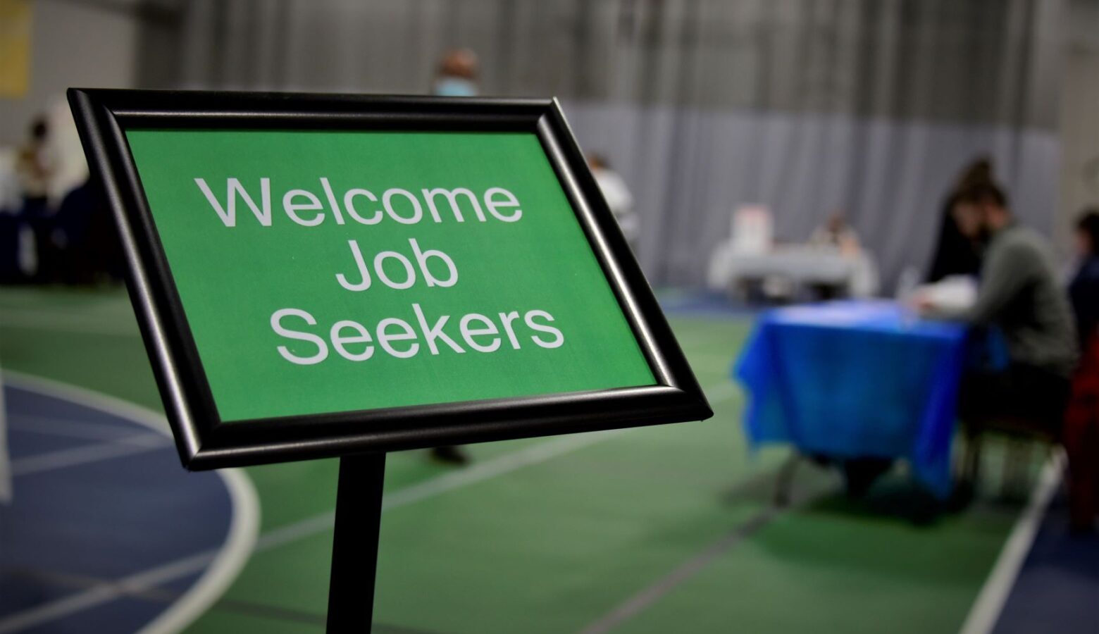 There is a black stand with a green sign inside that says "Welcome Job Seekers" in white letters.