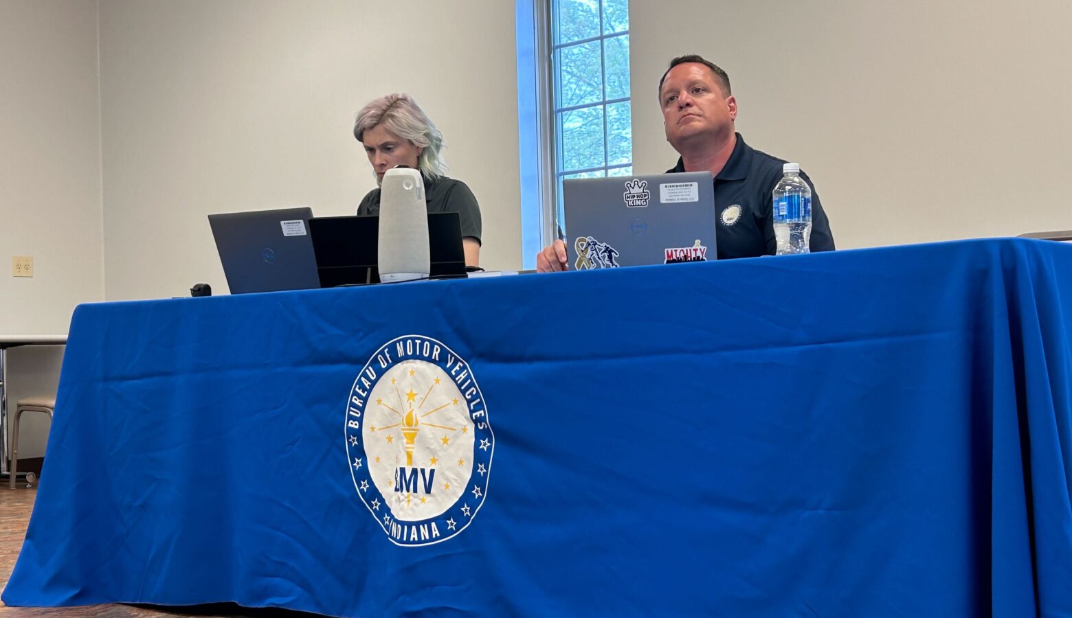 A man and woman sit at a table with a blue cloth over it.