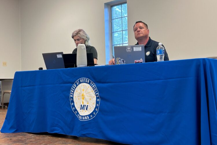 A man and woman sit at a table with a blue cloth over it.