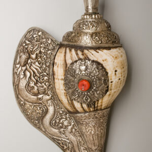 Ornate Tibetan conch shell horn wrapped in silver, featuring detailed floral and dragon motifs, a coral inlay, and a flared mouthpiece.
