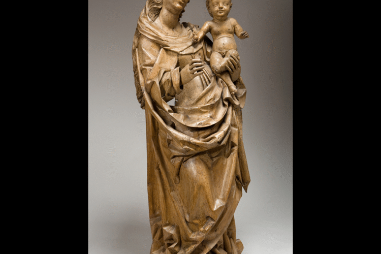 Wooden sculpture of the Virgin Mary holding the infant Christ. The Virgin stands in a contrapposto pose, with flowing, angular drapery and a serene expression. The Christ child is nude, standing upright on her arm and raising one hand in blessing.